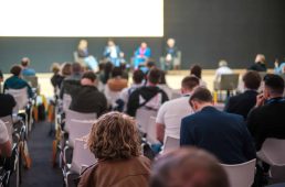 Audience listens to panel discussion at conference hall, rear view