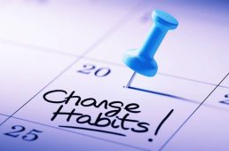 Concept image of a Calendar with a blue push pin. Closeup shot of a thumbtack attached. The words Change Habits written on a white notebook to remind you an important appointment.